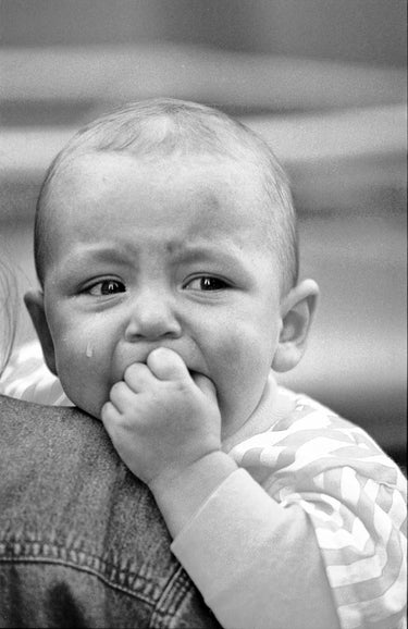 Baby mit Tränen in den Augen auf dem Arm seiner Mutter