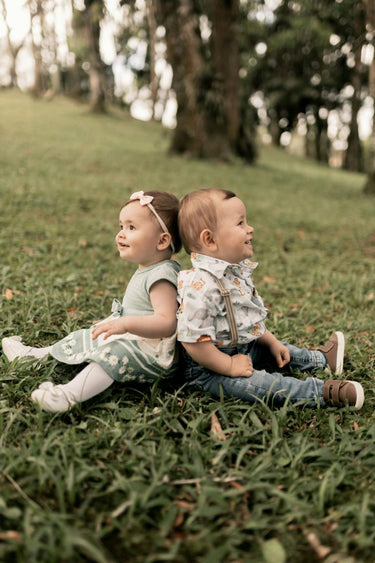 Ein Mädchen und ein Junge sitzen nebeneinander auf einer Wiese.